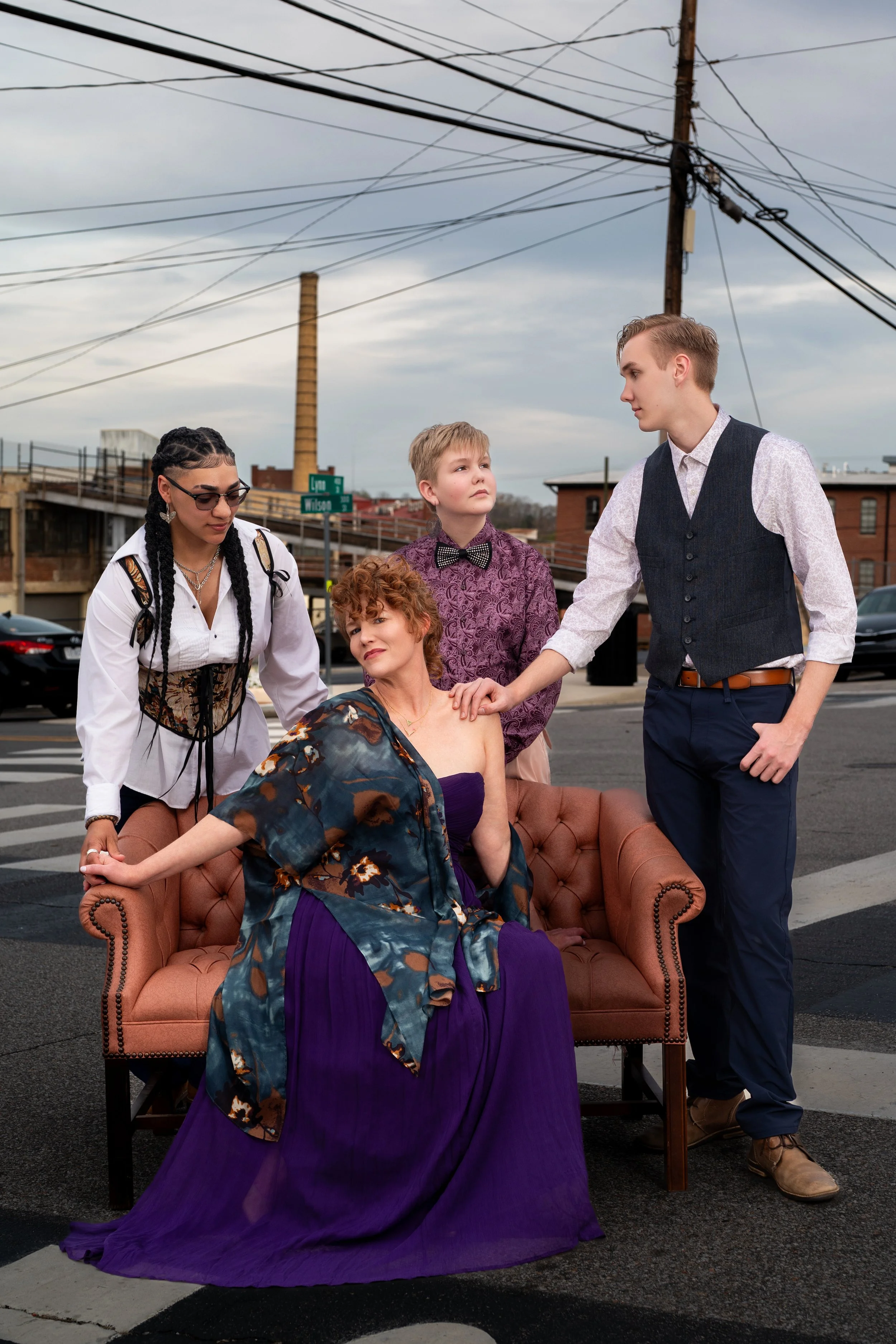 Four performers in vintage dress posed on leather armchairs in the middle of a downtown street