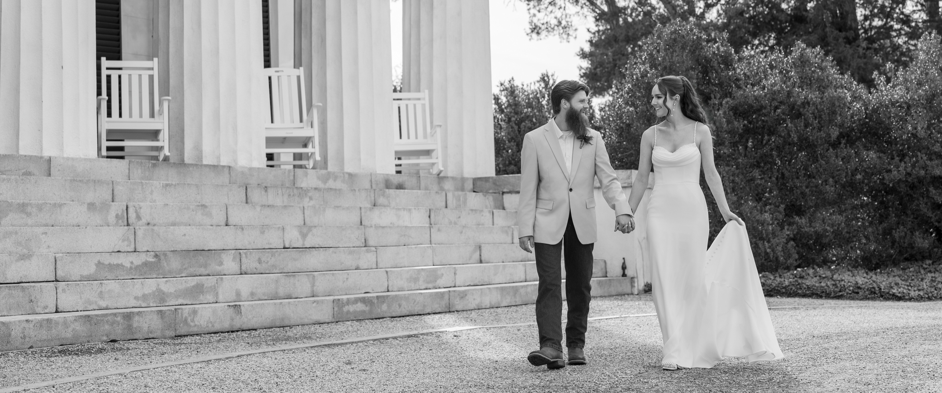 A bride and groom walking past the columns of their wedding venue