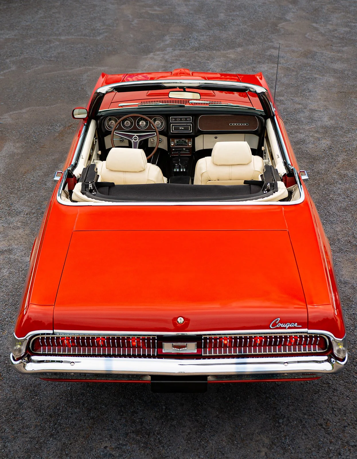 Overhead photograph of a restored bright red Mercury Cougar convertible with white interior