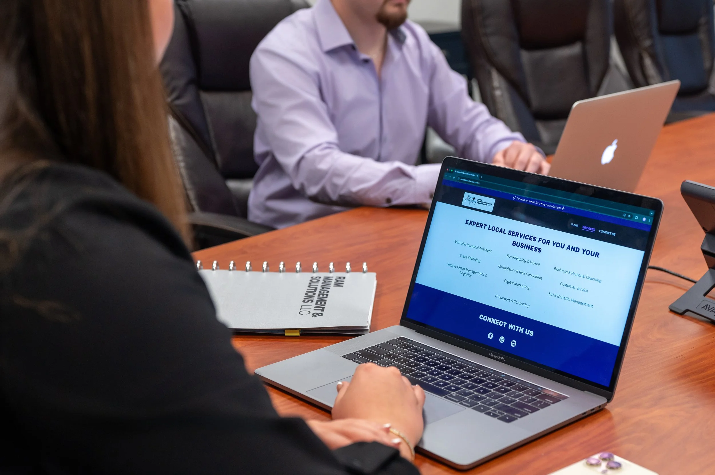 The RAM Management & Solutions team reviewing their new website on a laptop in a conference room